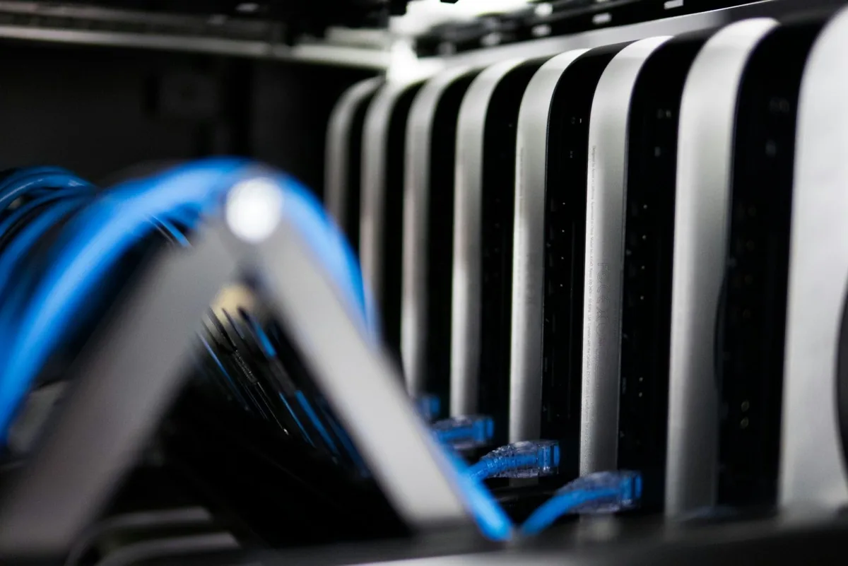 Blue network cables plugged into server blades in a dark rack